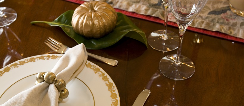 Simple Thanksgiving table decor with plates, silverware, and a pumpkin