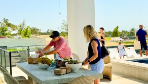 People gathered outside by the house pool to socialize, eat snacks, and enjoy the weather to celebrate the grand opening of Milestone Community Builder's new community, Milky Way at River Place.